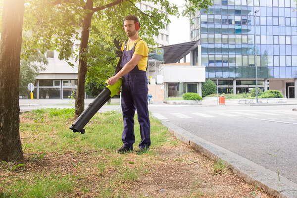 Gardener using his leaves blower in the garden