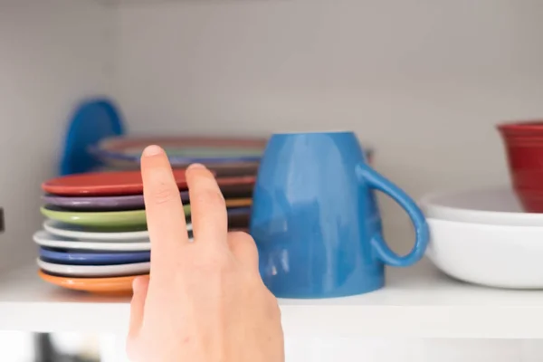 Женщина берет чашку из кухонного шкафа на завтрак — стоковое фото