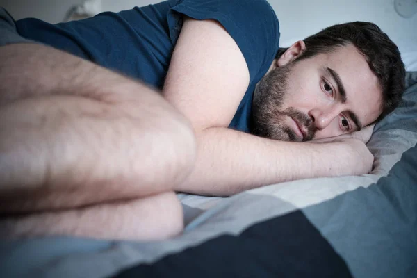 Депрессивный человек лежит в постели и чувствует себя плохо — стоковое фото