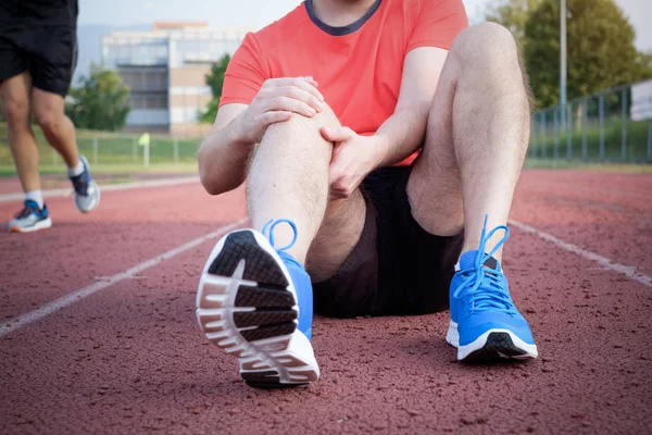 Löpare med skadade knä på spår — Stockfoto