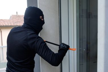 Hırsız levye kullanarak bir kapı kilidi zorlamak için çalışıyor