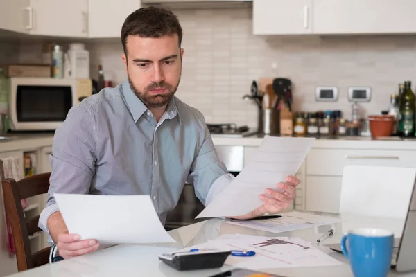 Hombre frustrado calculando cuentas y gastos de impuestos — Foto de Stock