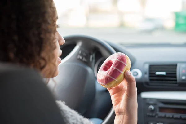 Женщина ест сладкое вождение автомобиля — стоковое фото