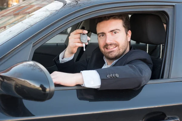 Hombre sosteniendo una llave de coche sentado en su vehículo — Foto de Stock