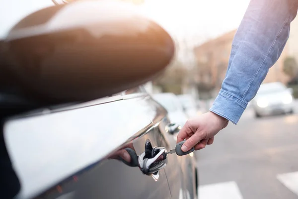 Mano sosteniendo una llave del coche y abriendo la puerta del coche — Foto de Stock