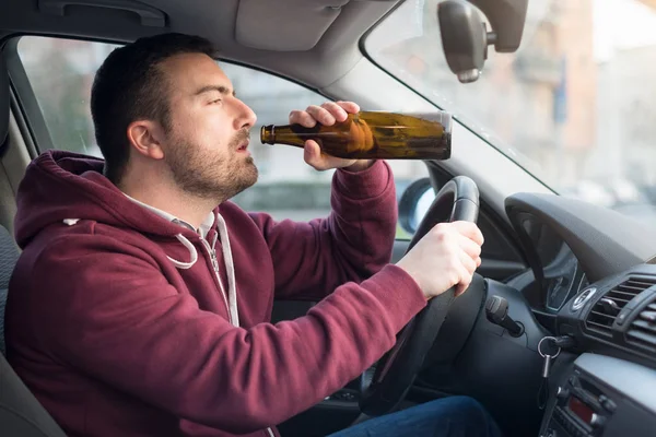 Drunk man driving car and drinking alcohol — Stock Photo, Image