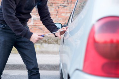 Thief trying to pick the lock of parked car clipart