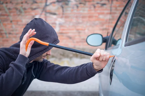 Tjuv försöker plocka låset på parkerad bil — Stockfoto