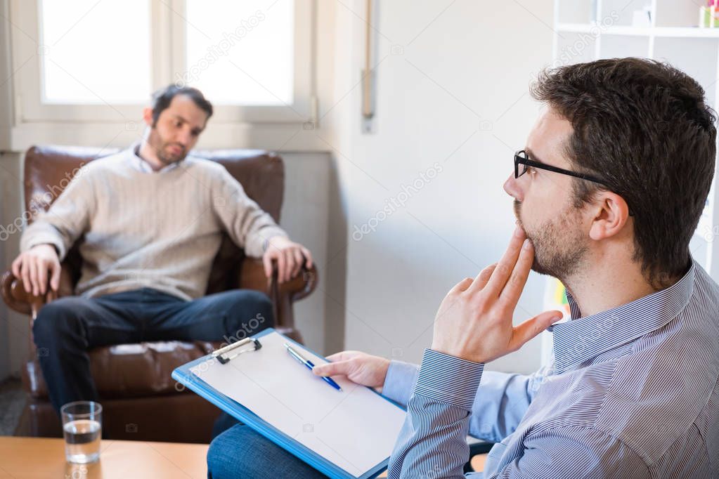 Psychologist taking notes during psychotherapy session