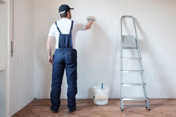 Trabalhador pintor profissional está pintando uma parede — Fotografia de Stock