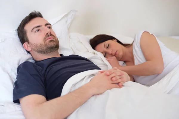 Triest en depressieve man liggend in het bed met zijn vrouw — Stockfoto