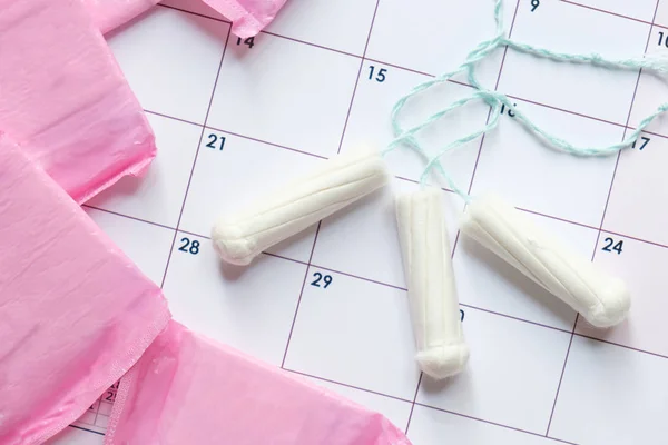 Menstrual tampons and pads on a calendar page — Stock Photo, Image