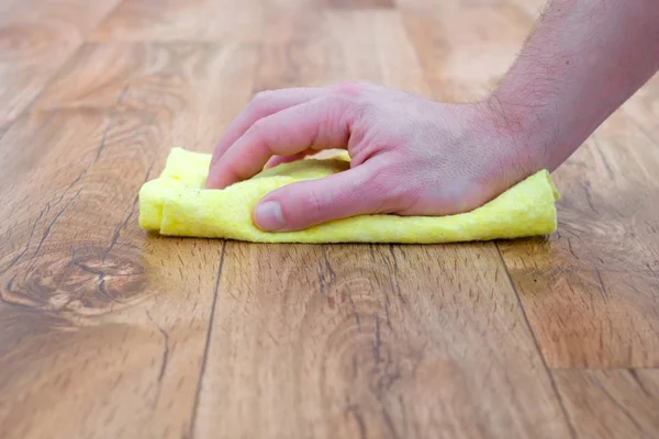 Detail of a hand with sponge cleaning a parquet floor