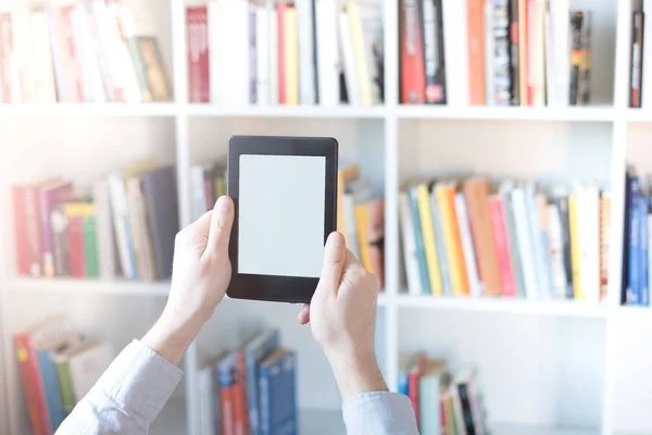 Lector de libros electrónicos en las manos en una librería —  Fotos de Stock