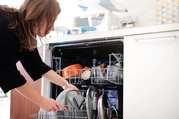 Mujer abriendo el lavavajillas en la cocina —  Fotos de Stock