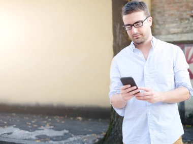 Onun smartphone bakmak ve şehir sokakta yürüme adam