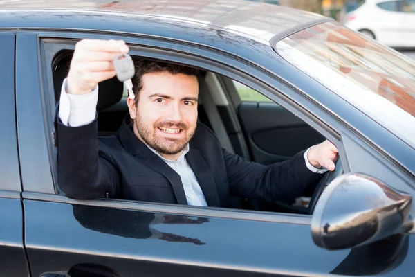 Feliz hombre sonriendo sentado en su coche sosteniendo la llave — Foto de Stock