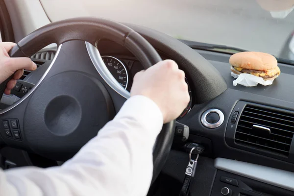 Člověk jíst nezdravé jídlo a řízení sedící v autě — Stock fotografie