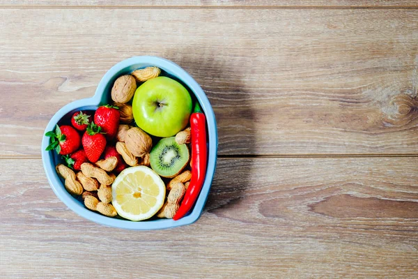 Plat en forme de coeur avec légumes isolés sur fond en bois — Photo