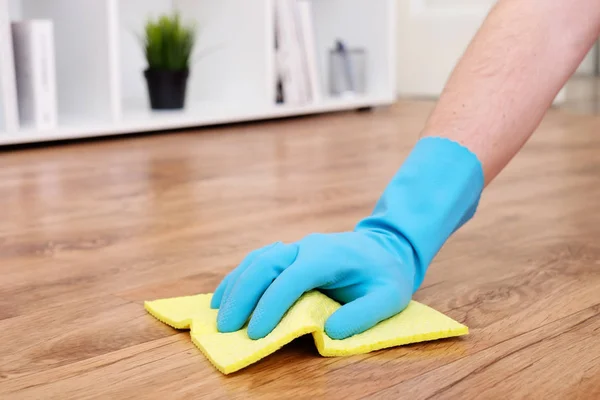 Una mano limpiando un suelo de parquet con una esponja —  Fotos de Stock