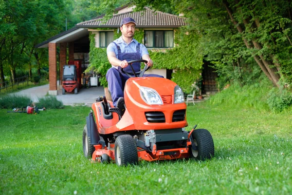 Jardineiro dirigindo um cortador de grama equitação no jardim — Fotografia de Stock