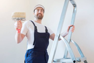 Adam boyama araçları tutarak bir duvar boyası için hazır