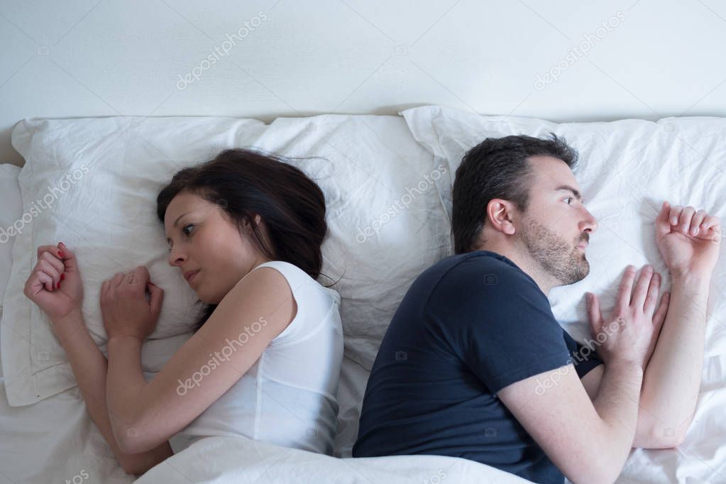 Sad and thoughtful couple after arguing lying in bed