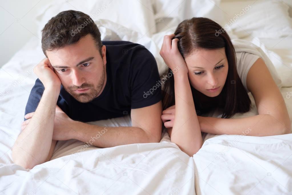 Worried and bored lovers couple after a fight lying in bed