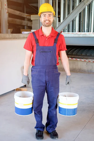 Pracovník podniku kbelíky na staveništi — Stock fotografie