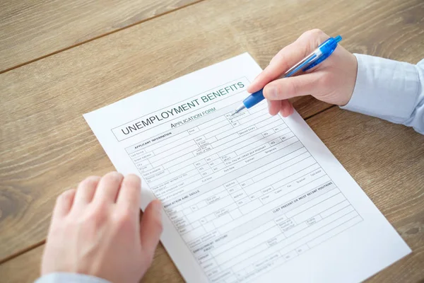Hand filling the unemployment benefit application — Stock Photo, Image