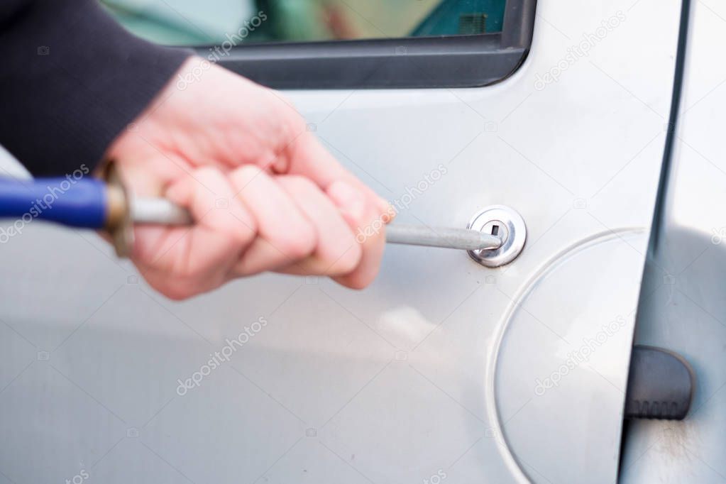 Thief trying to pick the lock of parked car