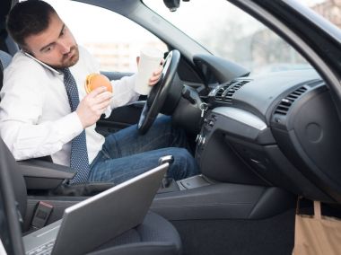 Bir hamburger yiyor ve adam arabaya oturmuş