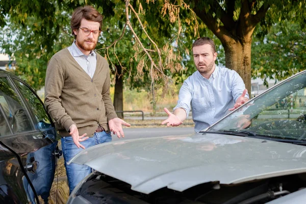 Dos hombres discutiendo después de un accidente de coche en la carretera — Foto de Stock