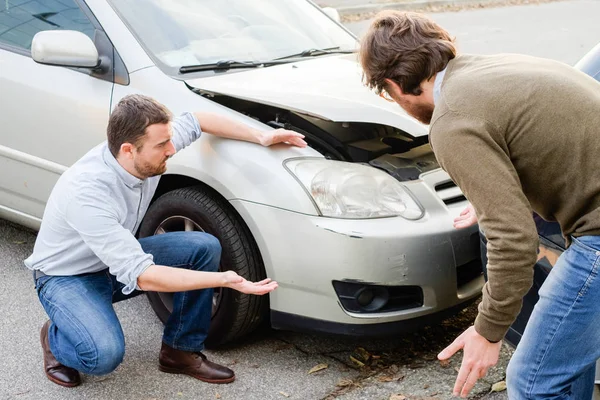 Dos hombres discutiendo después de un accidente de coche en la carretera — Foto de Stock