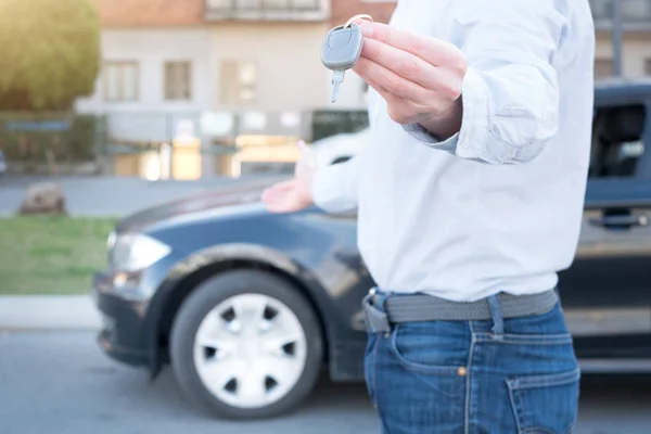 Hombre sosteniendo una llave de coche junto a su vehículo — Foto de Stock