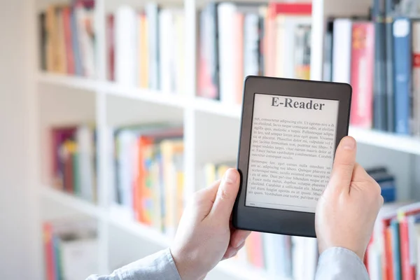 E-book reader in hands in a bookstore — Stock Photo, Image