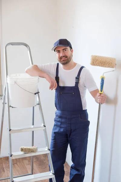 Homem pronto para pintar uma parede segurando ferramentas de pintura — Fotografia de Stock