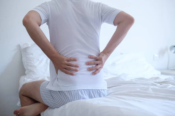 Hombre sintiendo dolor de espalda en la cama después de dormir —  Fotos de Stock