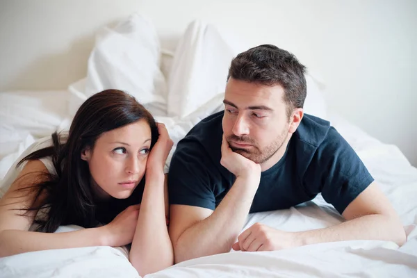 Worried and bored lovers couple after a fight lying in bed