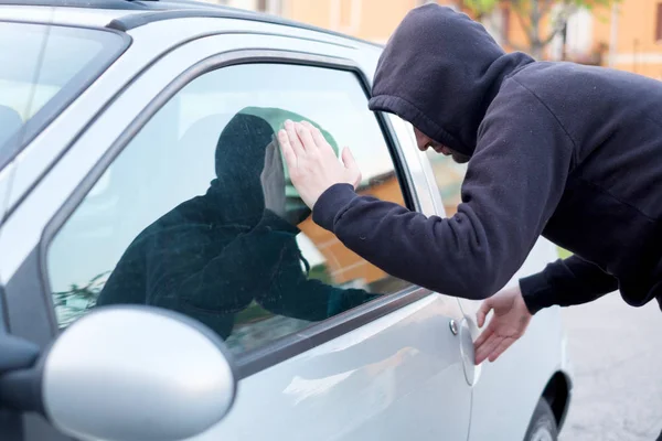 Voleur regardant à l'intérieur d'une fenêtre de voiture prêt à voler — Photo