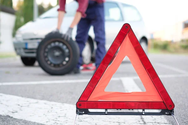 Hombre cambiando un neumático pinchado en el lado de la carretera — Foto de Stock