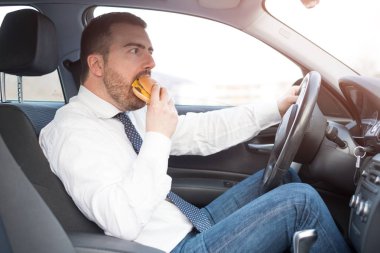 Bir hamburger yeme ve arabada oturmuş sürüş adam
