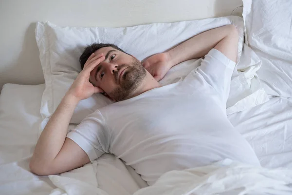 Hombre trastornado tratando de dormir en su cama por la noche —  Fotos de Stock