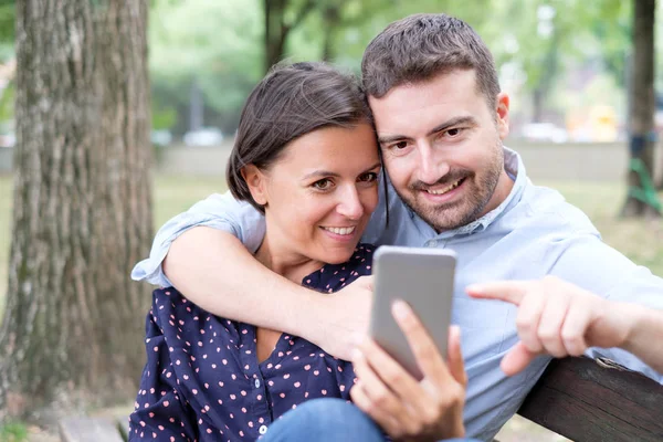 Szerelmes pár figyel a média elégedett-ra mozgatható telefon — Stock Fotó