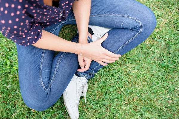 Молодая девушка, сидящая на траве в повседневной одежде — стоковое фото
