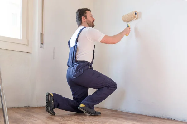 Trabalhador pintor profissional está pintando uma parede — Fotografia de Stock