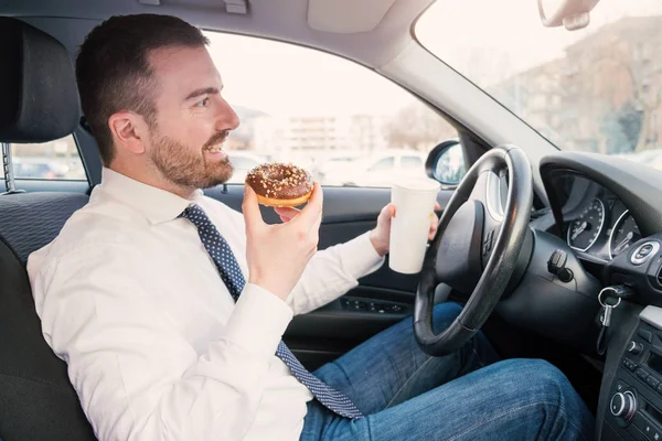 Hombre desayunando y conduciendo sentado en coche — Foto de Stock