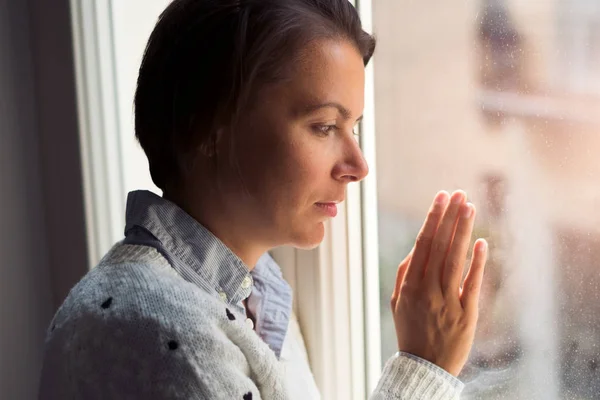 Desperate and sorrowful woman portrait next to window — Stock Photo, Image