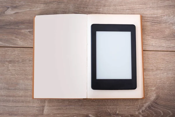 Lector de libros electrónicos en una mesa de madera con libro — Foto de Stock