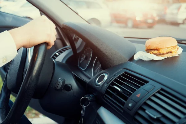 Hombre comiendo comida chatarra y conduciendo sentado en el coche — Foto de Stock